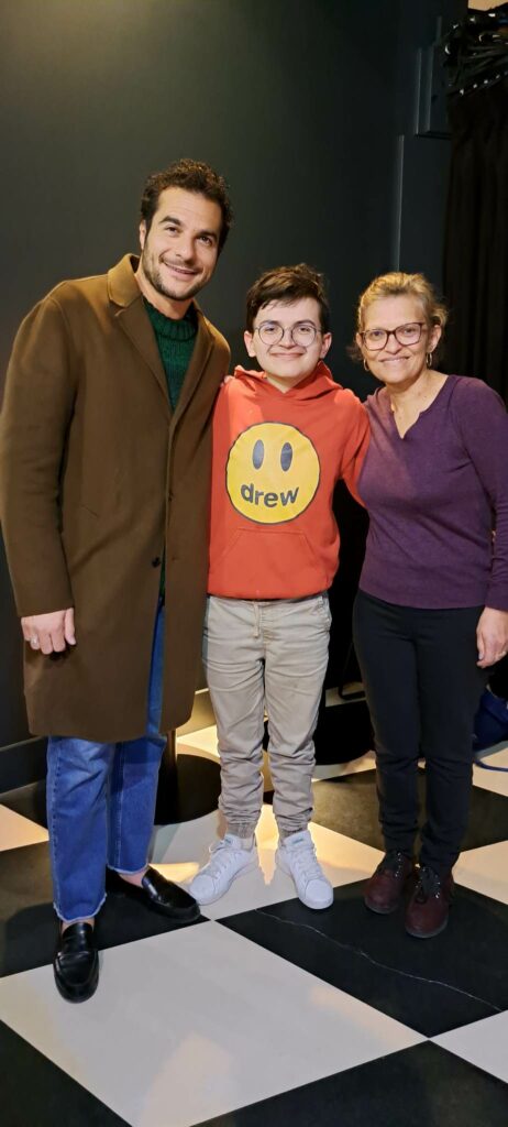 Photo de Raphy avec un grand sourire entouré de son idole le chanteur Amir et de sa courageuse et adorable maman Maylis